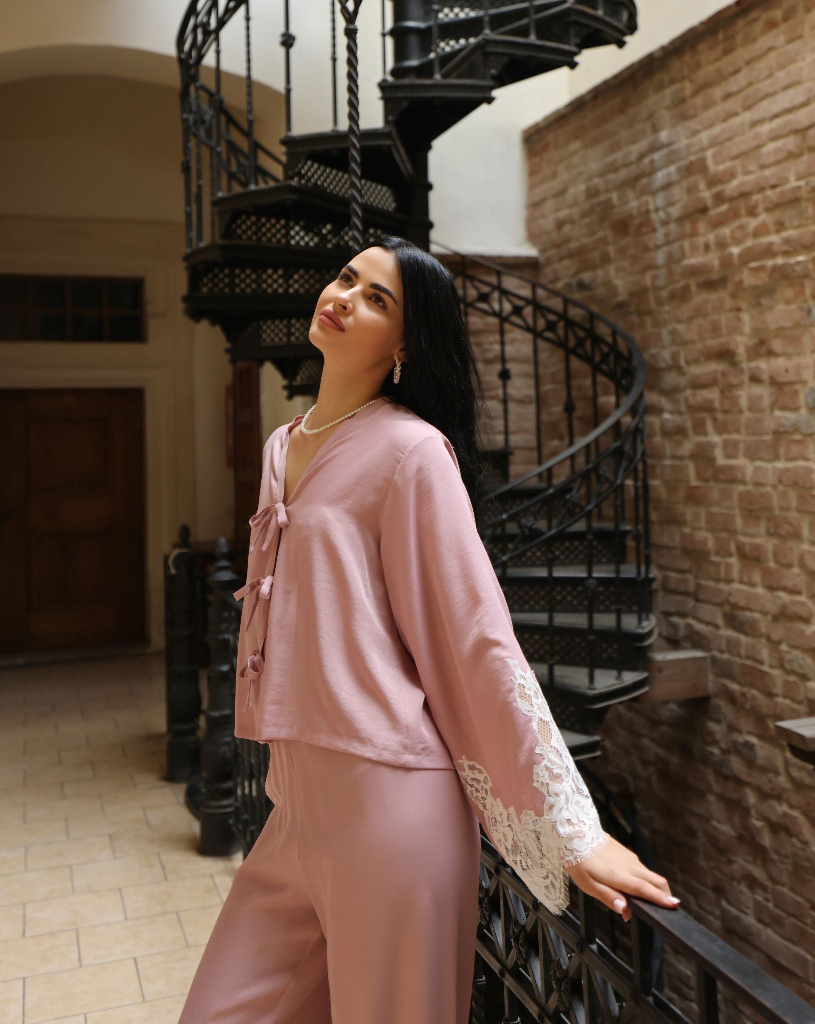 A mid-length shot of a woman leaning against a railing, highlighting the soft and fluid drape of the viscose fabric.