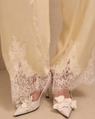 A detailed close-up of the trousers' hem, focusing on the lace accents that soften the silhouette without excess.
