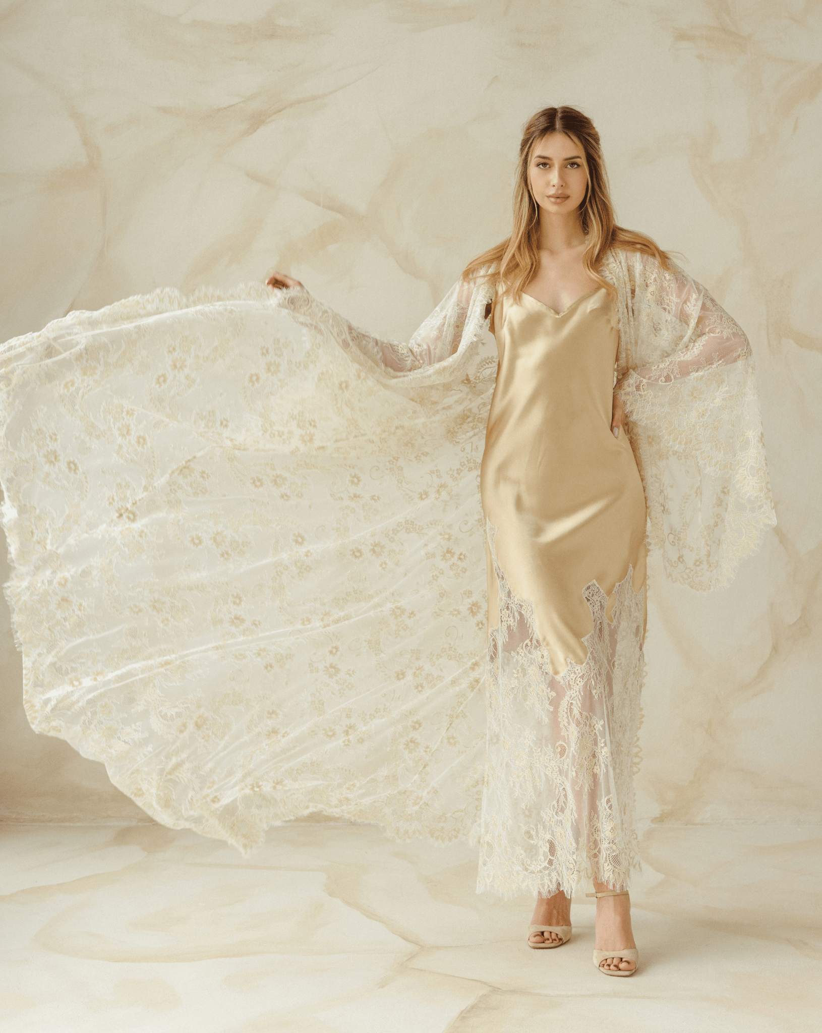 Woman posing in beige lace robe and nightgown set, holding robe to show full lace detail