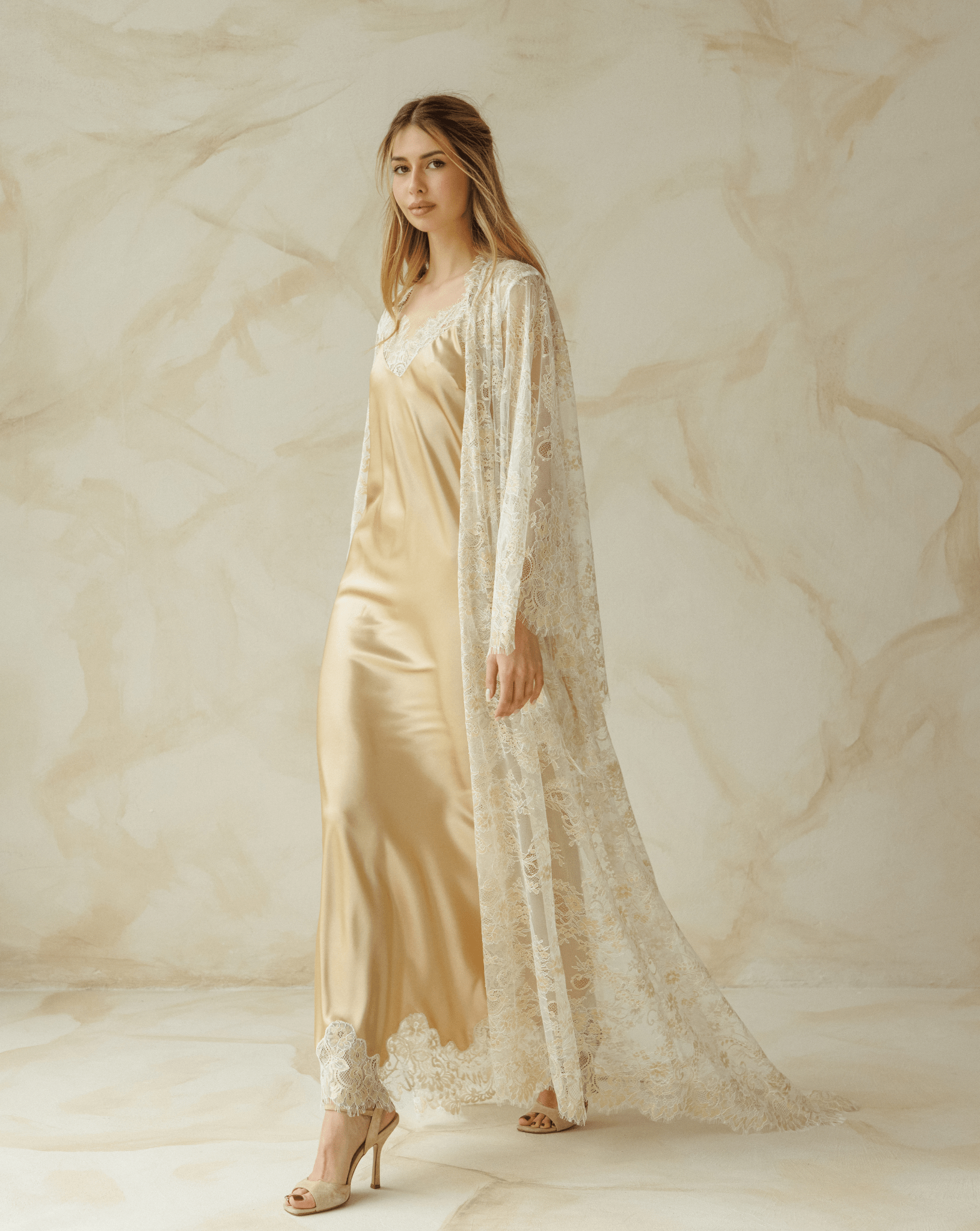 Woman wearing a beige satin nightgown with lace robe draped over shoulders