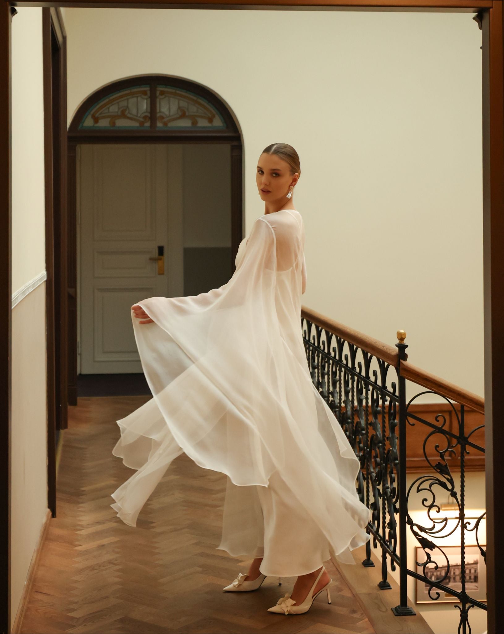 Dynamic shot of a sheer white silk robe in a swirl, emphasizing the weightless layer and romantic bridal design.