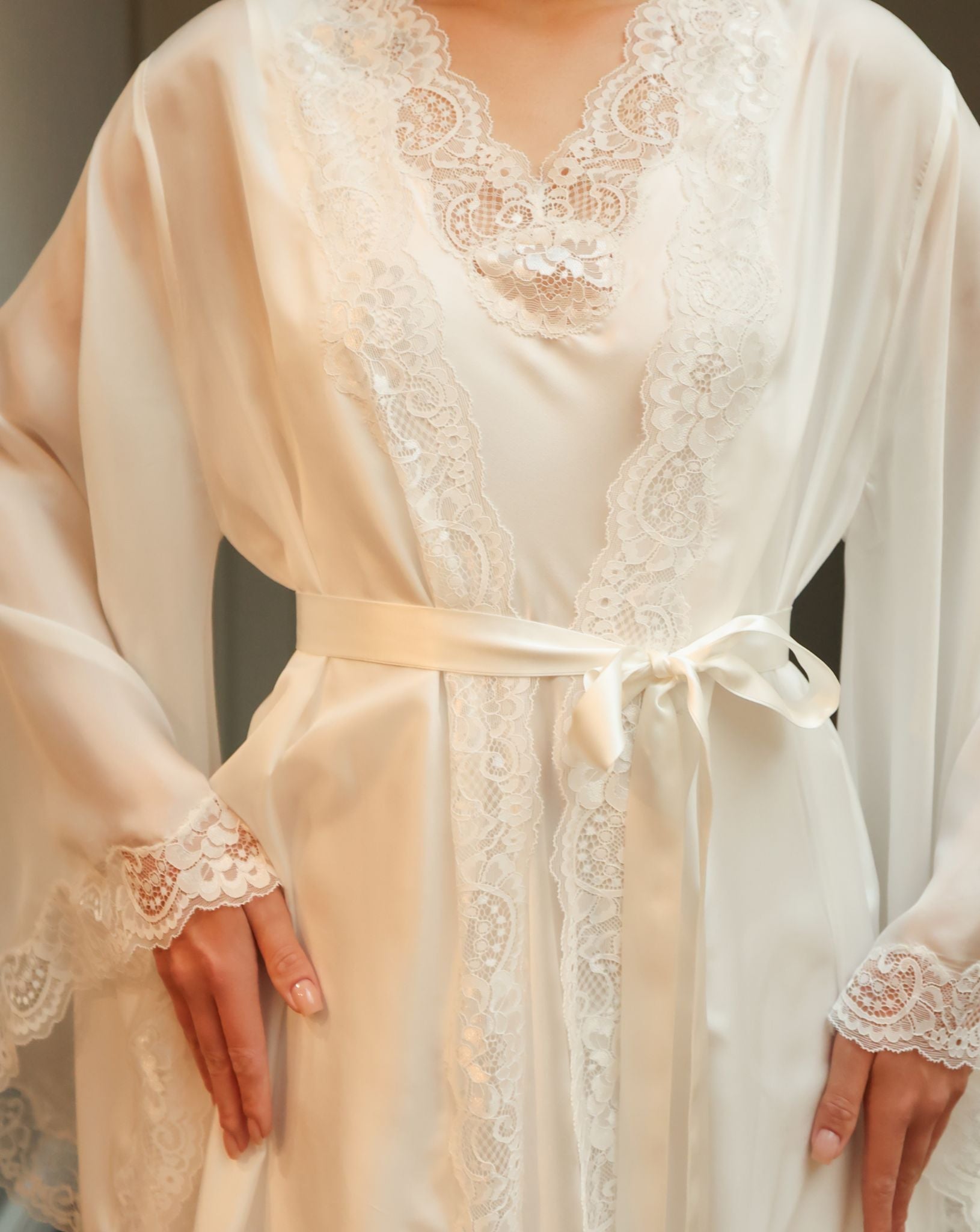 Detailed shot from neck to hips, focusing on the tied silk waist belt and the precise stitching of the wrap-over style.